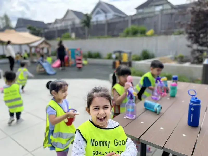 Children in safety vests enjoying snack time in the outdoor play yard.