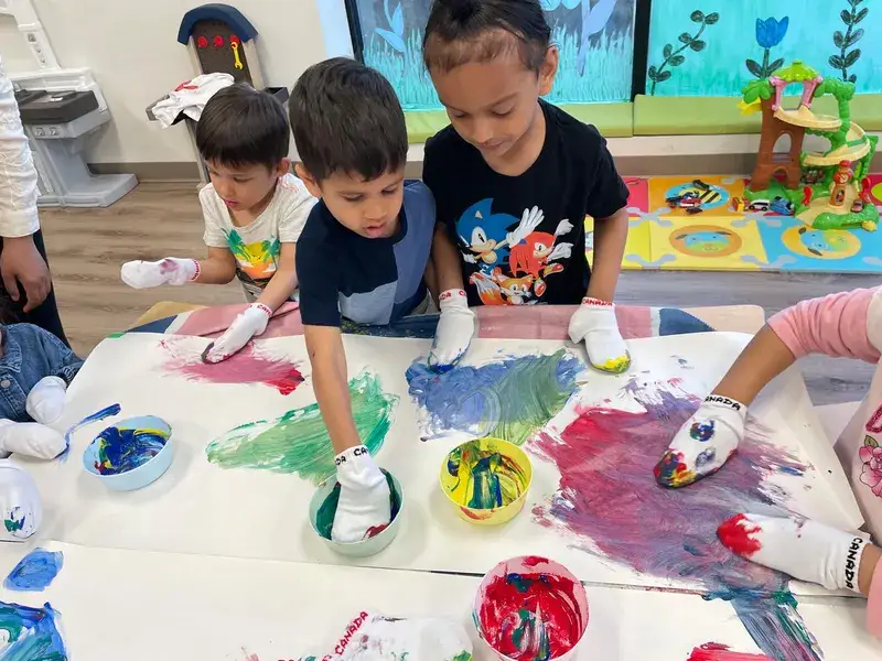 Children finger-painting with bright colours across a shared table.