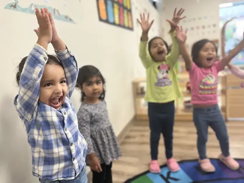 Children stretching their arms high during a movement activity.
