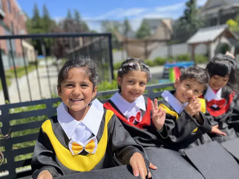 Smiling graduates in caps and gowns sitting together outdoors.